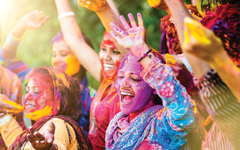 Indian women celebrating Holi with their hands up in the air