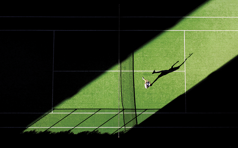 Shadow of tennis player on grass court