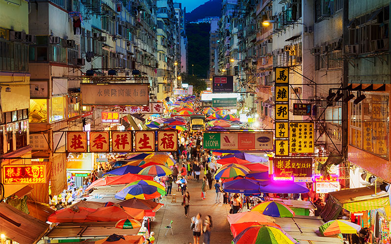 Market stalls lining a street between tall buildings