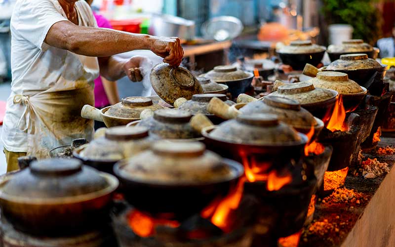 Malaysia Street Hawker cooking Clay pot Chicken Rice in night market at Kuala Lumpur