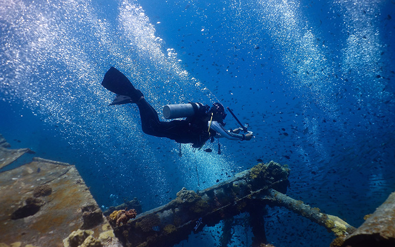 Diver underwater exploring a shipwreck in Malaysia