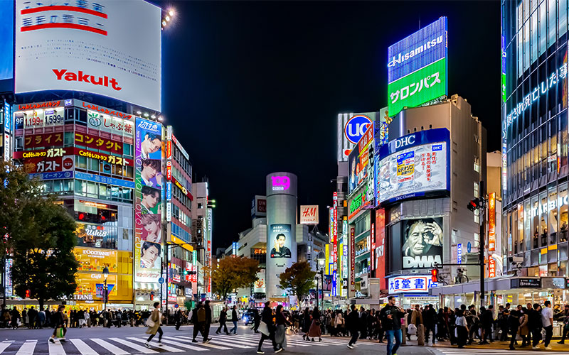 Busy Shibuya district with padestrians crossing large intersection 