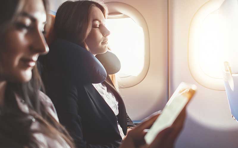 Two women seated on a plane next to the window