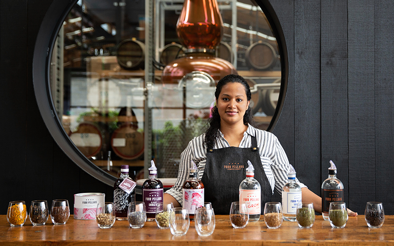 Staff standing behind counter with Four Pillars Gin bottles and glasses