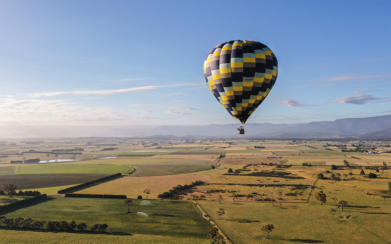 Hot air ballon in the sky overlooking green land