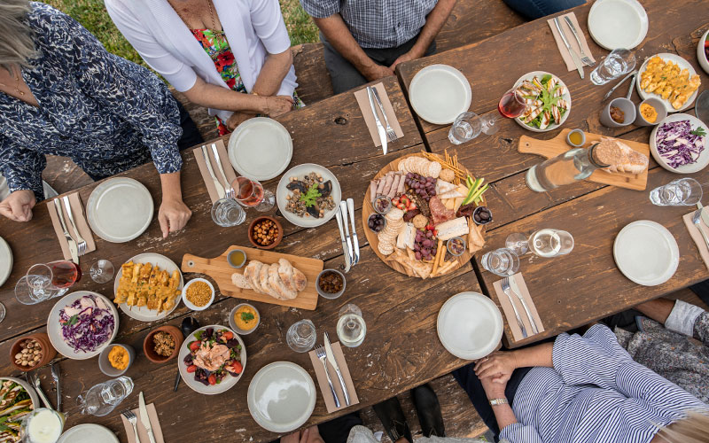 People seated at wooden table with share plates and drinks