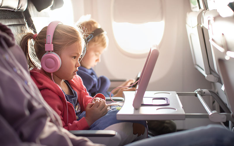 A girl and boy child sitting near the window seat on an airplane